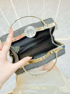 Detail view of sparkly black evening clutch with crystal clasp and golden ring handles