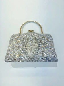 Macro shot of silver evening bag featuring radiant rhinestone patterns and gold top handle