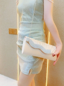 Dettaglio di borsa da sera in seta plissettata beige con strass ondulati e catena sottile