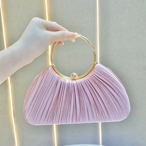 Detailed texture of pink pleated satin evening bag with round gold metal handle