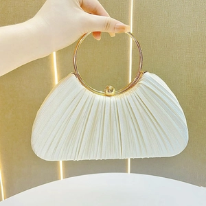Close-up of white pleated evening bag featuring a gold metal circular handle and texture