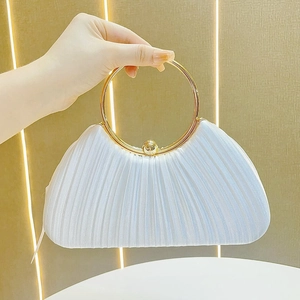 Detail of white pleated evening bag featuring a gold round handle and spherical metal clasp
