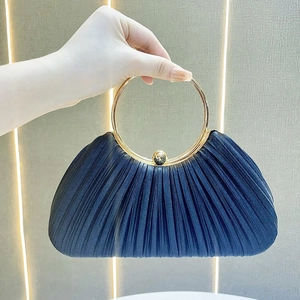 Detail of navy blue pleated evening bag with large gold round handle and ball clasp