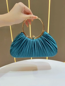 Detail of teal pleated satin evening bag featuring a round golden metal handle