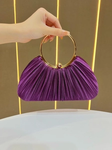 Detailed view of dark purple pleated evening bag with elegant golden ring handle