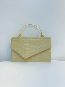 Macro view of gold evening clutch featuring pleated fabric texture and round metal handle