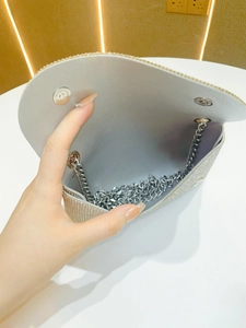 Detail showing the silver rhinestone evening bag with chain strap and magnetic snap