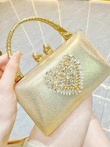 Detailed close-up of a gold evening clutch with heart-shaped crystal patterns and handle
