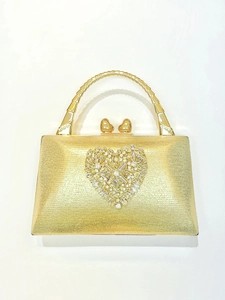 Detail of gold evening clutch with heart shaped rhinestone inlay and bamboo style handle
