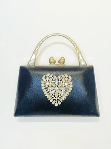 Detailed view of luxury black evening clutch with heart diamond buckle and metal handle