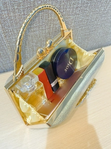 Detailed top view of gold evening clutch bag with sparkling finish and bamboo metal handle