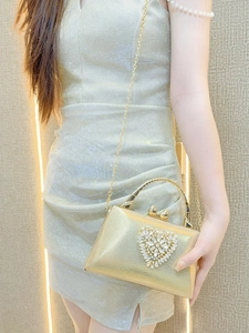 Elegant gold clutch bag with rhinestone heart detail shown on model for party attire