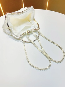 Detail view of cream evening clutch with metal ring handle and pearl shoulder straps