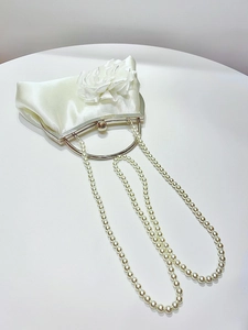 Detailed view of white satin evening bag with 3D fabric rose and pearl chain straps