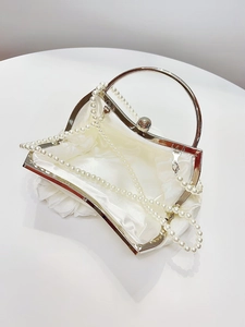 Detail of white satin evening bag featuring a 3D floral accent and silver metal handle