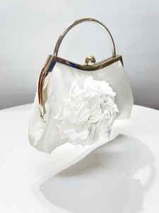 Detail of elegant white satin evening clutch featuring a large 3D floral accent and ring handle