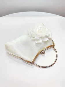 Detail view of white satin evening clutch featuring 3D rose and silver ring handle