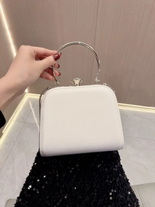 Dettaglio di una pochette da sera in pelle bianca con manico tondo argento e chiusura gemma