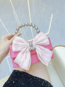Close-up of fuchsia satin evening bag with pink bow and crystal-studded rabbit detail