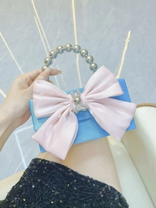 Detail of blue satin evening bag with pink organza bow and pearl bead handle