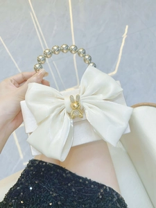 Detail of white satin evening bag with a large bow, rhinestone rabbit and bead handle