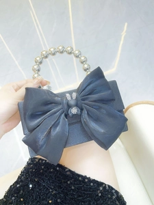 Detail of black satin evening bag featuring a large bow and rhinestone bunny ornament