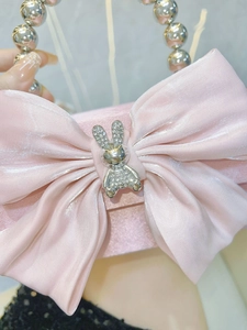 Detail of pink satin evening bag with silk bow, rhinestone rabbit and pearl handle