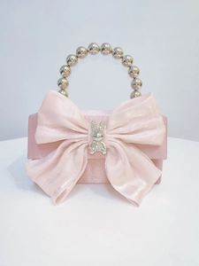 Detail of pink satin evening bag with a large bow, rabbit charm, and beaded handle