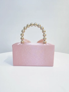 Detail of pink satin evening clutch featuring beaded metal handle and ribbon bow