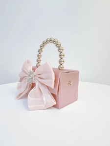 Detail view of pink satin evening bag with pearl handle and silk bow and bunny buckle
