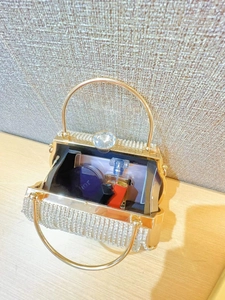 Detail of evening bag interior showing capacity for lipstick and perfume on wooden desk
