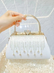 Detail of white evening bag featuring rhinestone tassels and a gold crystal clasp