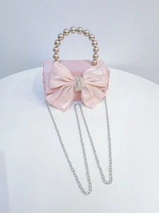 Close-up of pink satin clutch featuring a large bow with rhinestone and beaded handle
