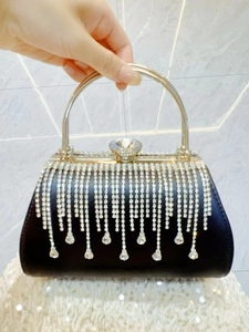 Detail of elegant black evening bag with silver rhinestone tassels and round metal handle