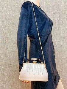 Detail of evening bag with pearl texture and crystal fringe on blue velvet dress