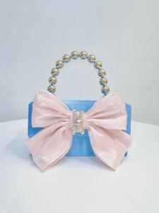 Detailed view of the pink satin bow and crystal rabbit charm on a blue glitter evening bag