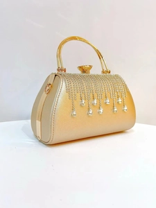 Detail of golden evening bag featuring rhinestone tassels and a metal handle