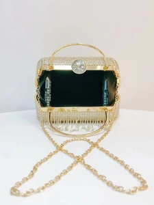 Detailed shot of open evening bag with gold rhinestones, ring handle, and fringe