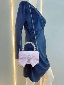 Pink satin evening bag with a large bow, pearl handle, and diamond rabbit buckle detail