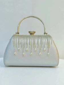 Detail of silver evening clutch featuring rhinestone tassels and a large gemstone clasp