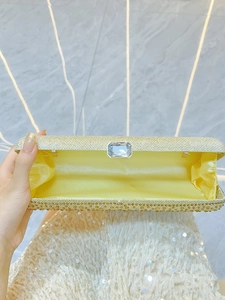 Golden shimmering evening clutch bag with crystal clasp and satin interior storage