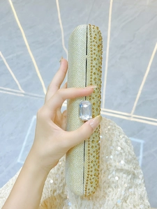 Detailed macro view of champagne gold evening clutch with rhinestones and crystal clasp