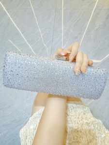 Detail showing high-density white rhinestones and clear clasp on a silver evening bag