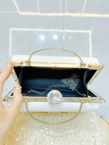 Elegant white evening clutch bag with crystal lock and gold handle shown open with chain
