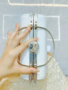 Detailed macro view of white evening bag featuring a large central sparkling round crystal