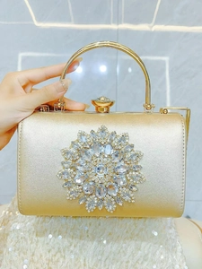 Detail of luxurious gold evening clutch featuring a large radial rhinestone floral center