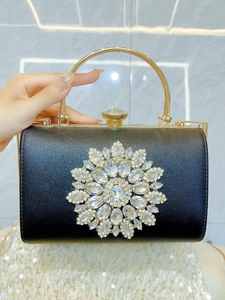 Close-up of luxury black evening bag with sparkling crystal floral cluster and gold handle