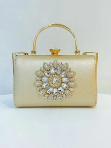 Detailed view of luxury gold evening clutch with crystal flower and metal top handle