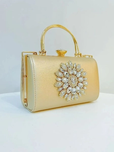 Detail of evening clutch bag featuring a large sunburst rhinestone flower and metal handle