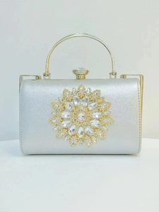 Detail of silver silk clutch bag with crystal flower ornament and metal handle